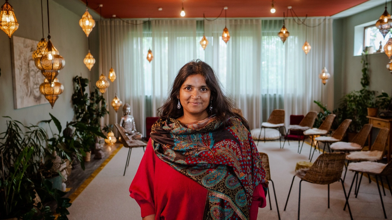 Sirima Miller – LEBENS(T)RAUM für Körper, Geist & Seele – eine Einzelperson bei einem scheinbar Wellness-Event oder einem ähnlichen Treffpunkt mit Bohème-Dekor.